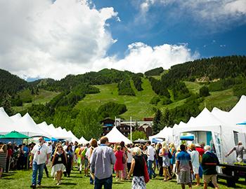 A crowd with white tents looking at Aspen Mountain