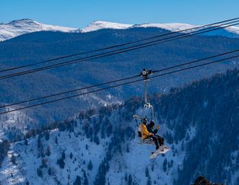 view of skier on Aspen chairlift with Independence Pass in the background