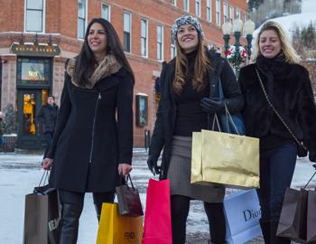 Shoppers passing by Aspen storefront windows