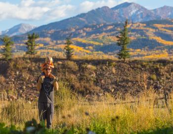 Man hiking with his child on his shoulders 