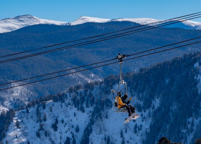 view of skier on Aspen chairlift with Independence Pass in the background
