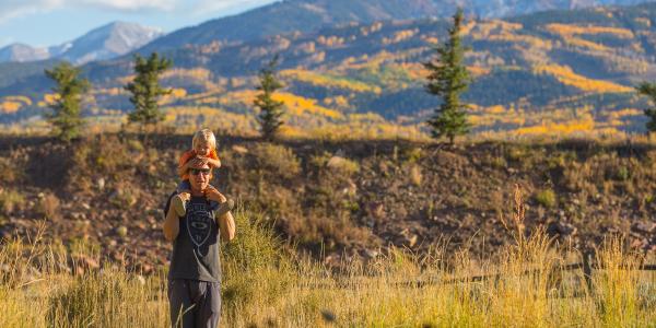 Man hiking with his child on his shoulders 