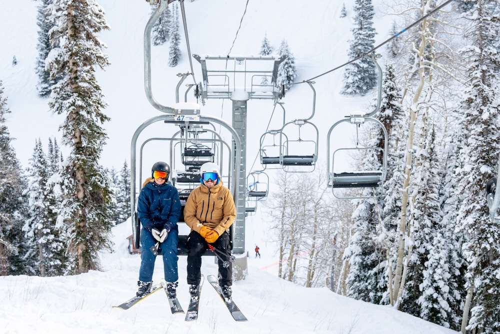 Two people riding a ski gondola to the top of the mountain.